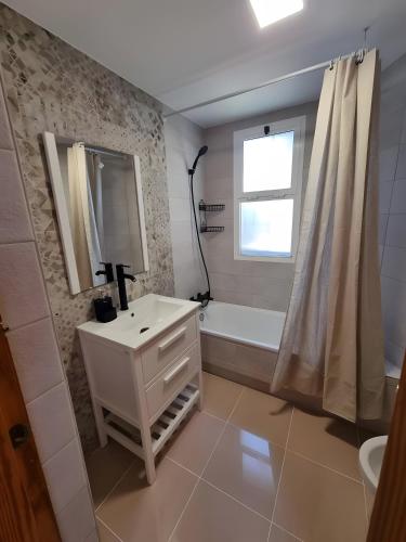 a bathroom with a sink and a tub and a mirror at Apartamento Rincón La Ballena in Rota