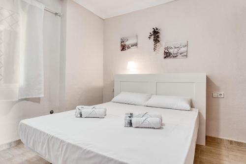 a white bedroom with a large white bed with two pillows at Sunflower Puerto Rico in Santa Pola