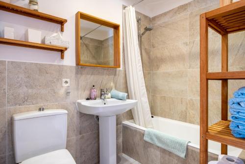 a bathroom with a toilet and a sink and a tub at Apartament Carla in Port de Soller