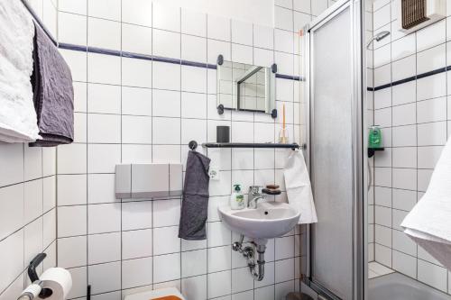 a white tiled bathroom with a sink and a mirror at Sonnige Wohnung im Markgräflerland in Efringen-Kirchen