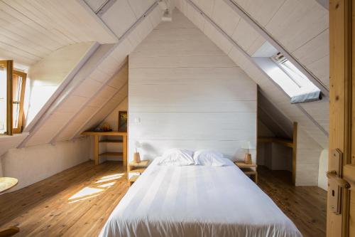 a bedroom with a large white bed in the attic at Moulin du Tourous - Chambre 1 in Plouédern