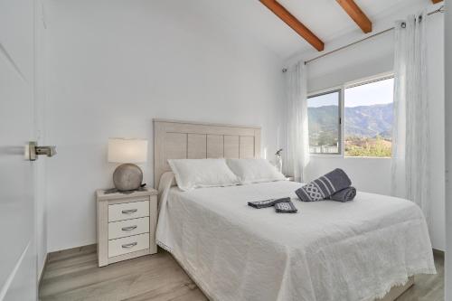 a white bedroom with a bed and a window at Entre montañas in Árchez