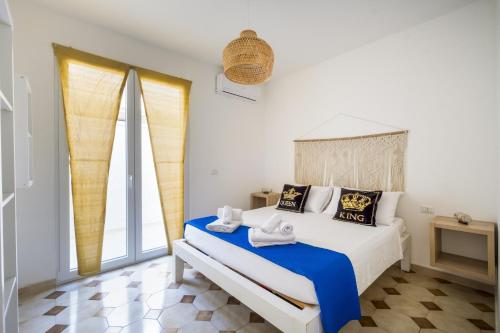 a bedroom with a white bed with blue sheets and a window at Blue Bay Lux House in Torre Lapillo
