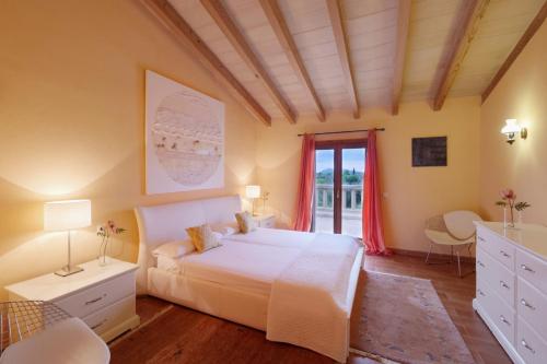 a bedroom with a large white bed and a window at Cas Cans in Artá