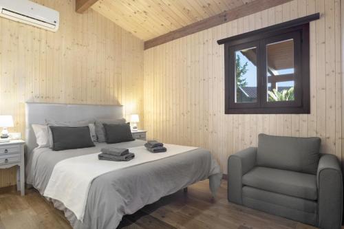 a bedroom with a bed and a chair and a window at Villa Fatema in Conil de la Frontera