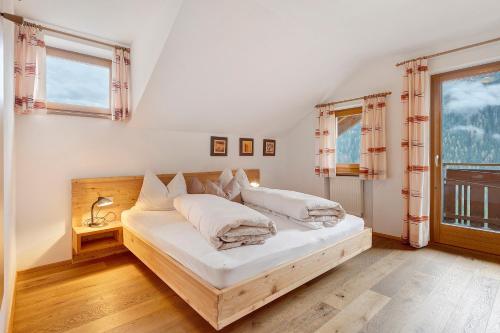 a bedroom with a bed with white sheets and a window at Mair am Tinkhof in Selva dei Molini