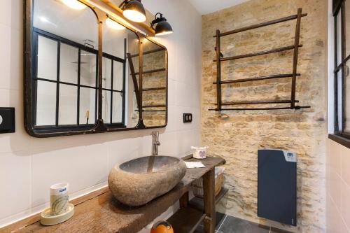 a bathroom with a stone sink and a mirror at Chambres D'hôtes La Baritaudière in La Réorthe