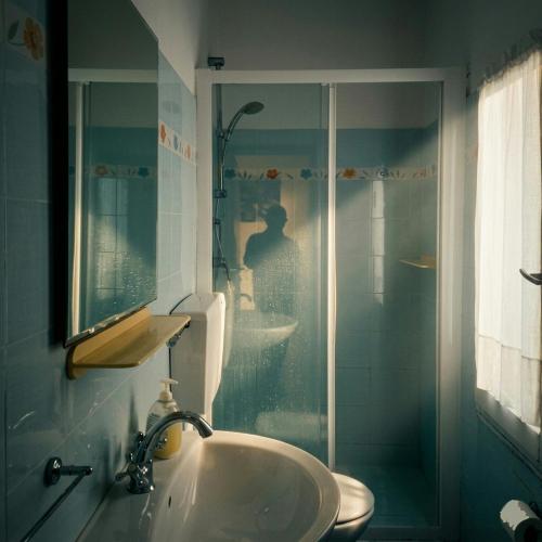 a bathroom with a sink and a glass shower at GTE singola in Poggio