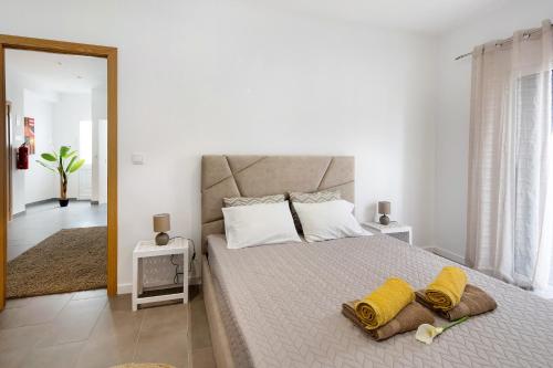 a bedroom with a large bed with yellow towels on it at Capelas Pdl Apartment in Capelas