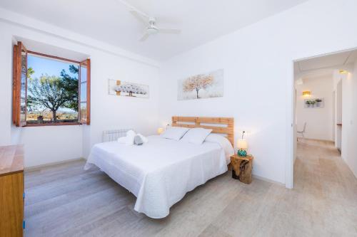 a white bedroom with a bed and two windows at Son Crespi Vell in Manacor