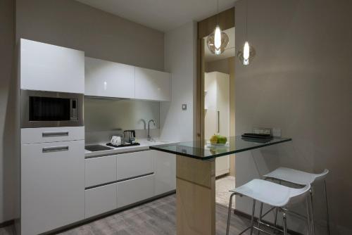 a kitchen with white cabinets and a black counter top at Eastin Residences Vadodara in Vadodara