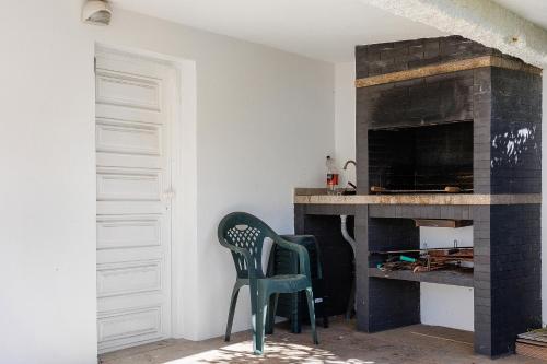 a living room with a fireplace and a green chair at Dunas Das Marinhas in Marinhas