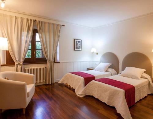 a bedroom with two beds and a chair and a window at Gran Castanyer in Viladrau