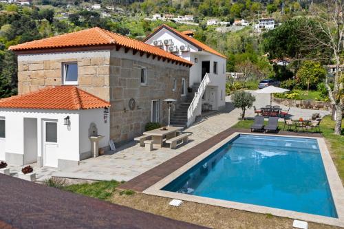 a villa with a swimming pool in front of a house at Quinta do Rio Douro - Turismo Rural in Paços de Gaiolo