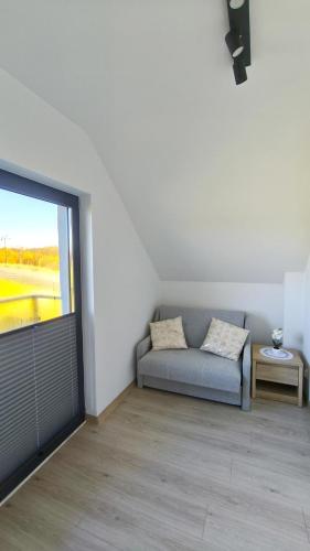 a living room with a couch and a large window at Domki i Apartamenty WiR na Kaszubach in Chmielno