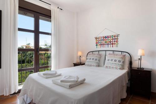 a white bedroom with a large bed with towels on it at Cobijadas75 Corredera in Vejer de la Frontera