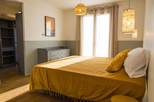 a bedroom with a bed with yellow sheets and a window at Bastide des vignes, piscine privée in Trèbes
