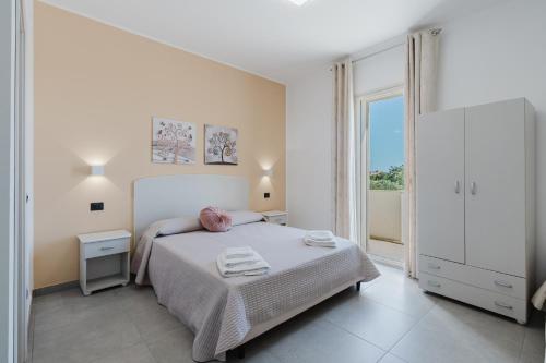 a white bedroom with a bed and a large window at Bed And Breakfast Champagneria in Castelvetrano Selinunte