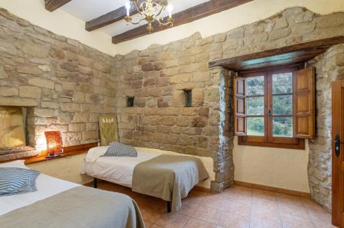 a bedroom with two beds and a stone wall at Mas Vinyoles in Centellas