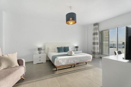 a white bedroom with a bed and a couch at Villa Aurora Playa La Arena in Puerto de Santiago