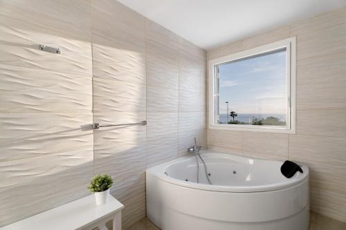 a white bath tub in a bathroom with a window at Villa Aurora Playa La Arena in Puerto de Santiago