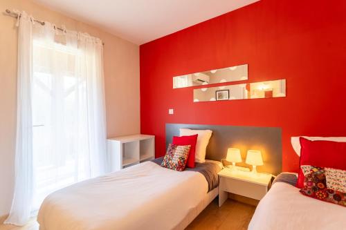 a red bedroom with two beds and a window at Chambre - Joubarbe in Aroue