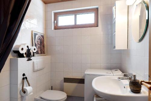 a white bathroom with a toilet and a sink at Wooden Western Lodge Tiny Haus in Brekendorf