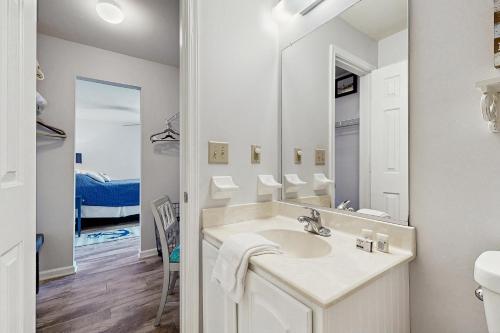 a white bathroom with a sink and a mirror at Sandy Bottom VROBX in Kitty Hawk