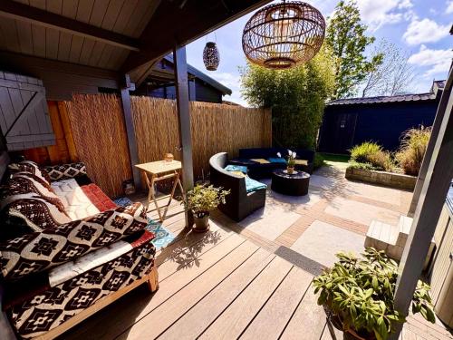 a patio with a couch and chairs on a wooden deck at 1001 Nights Luxury Spa Oasis with jacuzzi sauna and garden near Amsterdam in Vijfhuizen