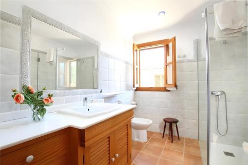 a bathroom with a sink and a toilet and a mirror at Villa L´Embat in Pollença