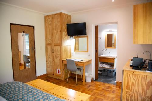 a room with a bed and a desk with a computer at 7 Ackermann Place Guest House in Stellenbosch