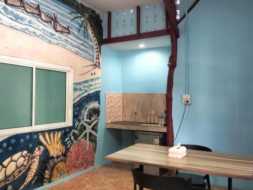 a dining room with a table and a mural on the wall at Happy house in Ban Khlong Son
