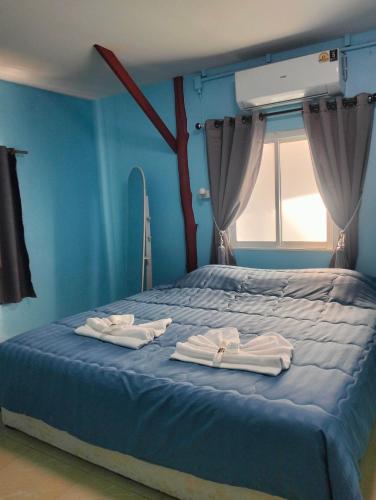 a blue bedroom with a bed with towels on it at Happy house in Ban Khlong Son