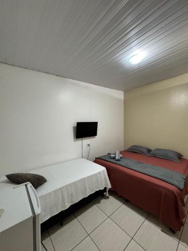 a bedroom with two beds and a flat screen tv at Pousada do Delta in Tutóia