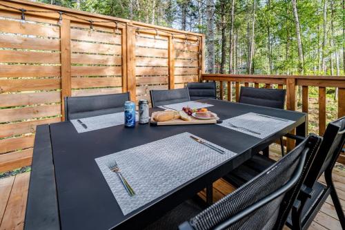 a black table with a plate of food on a deck at Le Taiga - Pool Table Nature Pet Friendly in Pont-Rouge