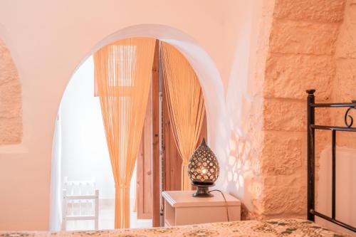 a bedroom with a bed and a lamp on a dresser at Villa Trullo Vecchia Aia in Alberobello