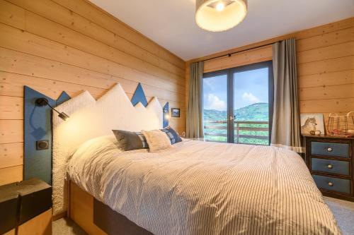 a bedroom with a large bed with a large window at Le Chalet Milien in La Bresse