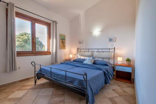 a bedroom with a bed with blue sheets and a window at Casa Nuages in Badesi
