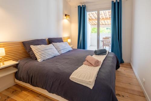 a bedroom with a bed with blue curtains and a window at Rose Antique in Valréas