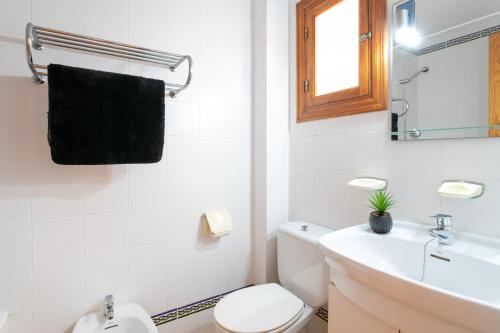 a white bathroom with a toilet and a sink at Playa Arenales del Sol in Arenales del Sol
