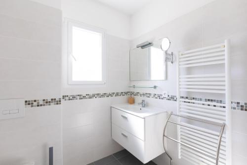 a white bathroom with a sink and a window at Residence Cismonte in Morosaglia