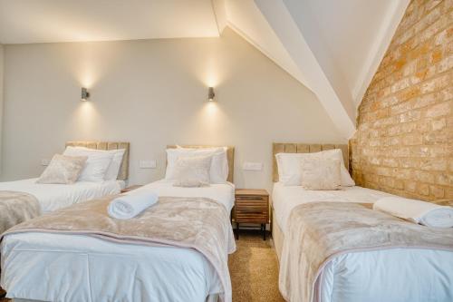 a room with three beds with white sheets at The Stuart Hotel in Liverpool