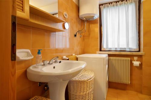 a bathroom with a sink and a toilet and a window at Appartamento Eva in Folgaria