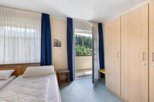 a bedroom with a bed and a window with blue curtains at Ferienheim Eisenbach in Eisenbach