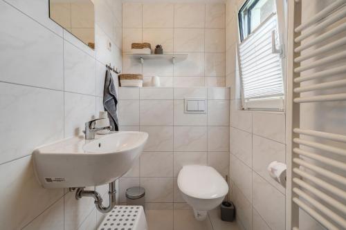 a white bathroom with a sink and a toilet at Baumfuchs Ferienbungalow in Wesenberg