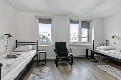 a bedroom with two beds and a chair and two windows at Key2Komfort in Duisburg