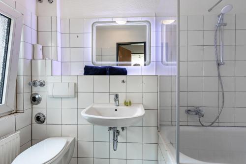 a bathroom with a sink and a toilet and a mirror at Key2Komfort in Duisburg