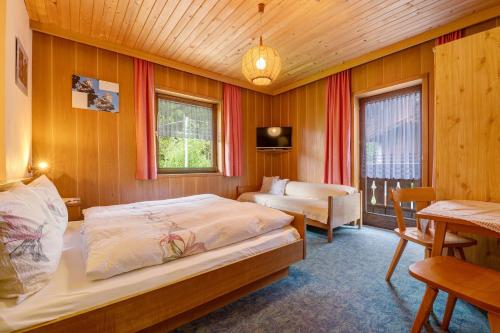 a bedroom with two beds and a table and a desk at Mittermüllerhof Feldthurns in Velturno