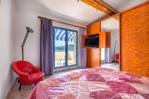 a bedroom with a bed and a red chair and a window at Appartement Numéro 2 - piscine in Valbonne