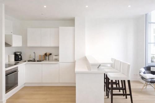 a white kitchen with white cabinets and chairs at Logement entier rue Sainte Catherine in Bordeaux